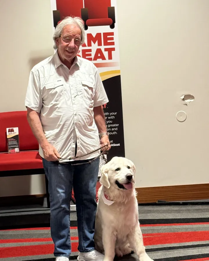 Ace, a Golden Retriever, sitting beside his handler Jon